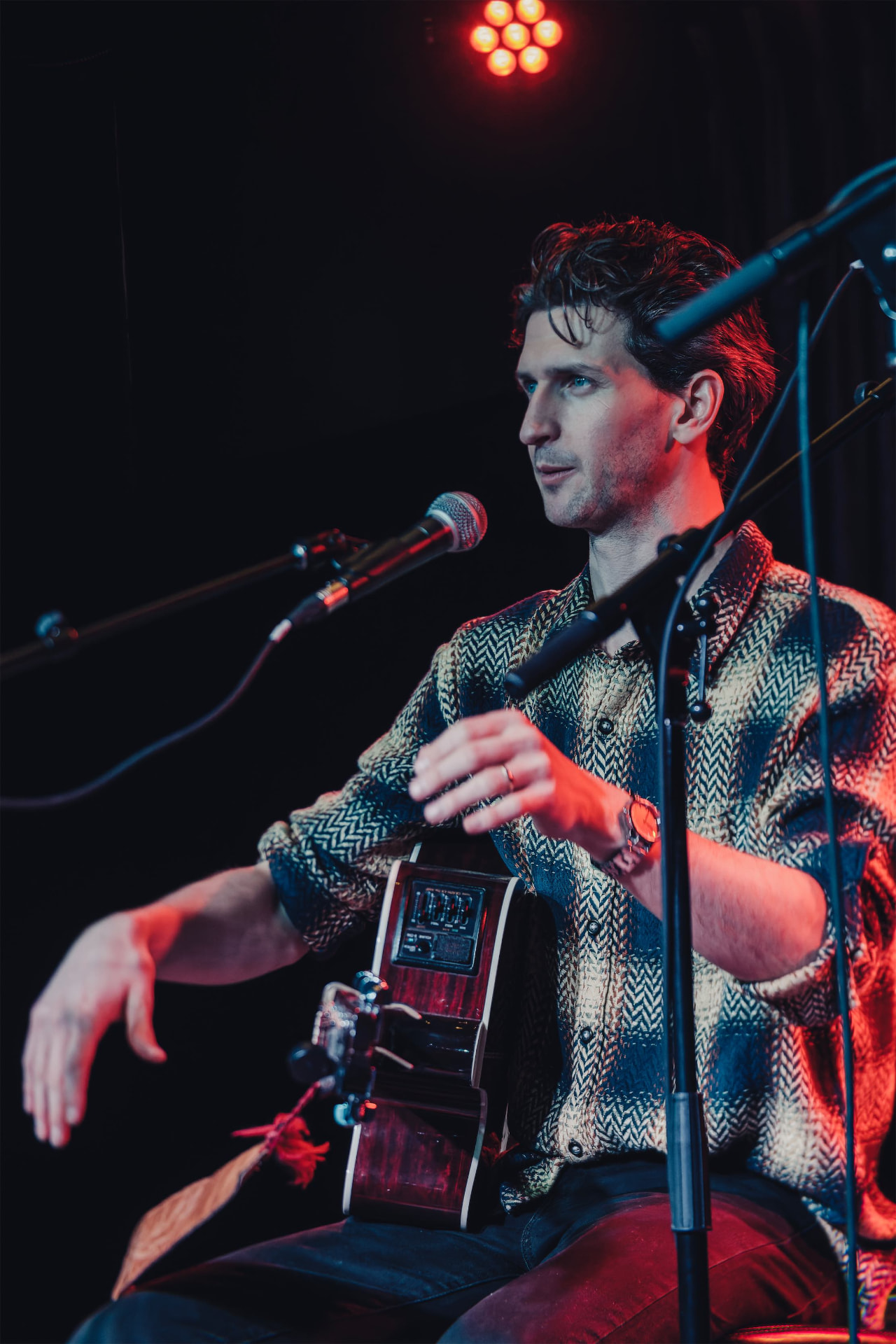 Charles performing with an acoustic guitar under stage lights